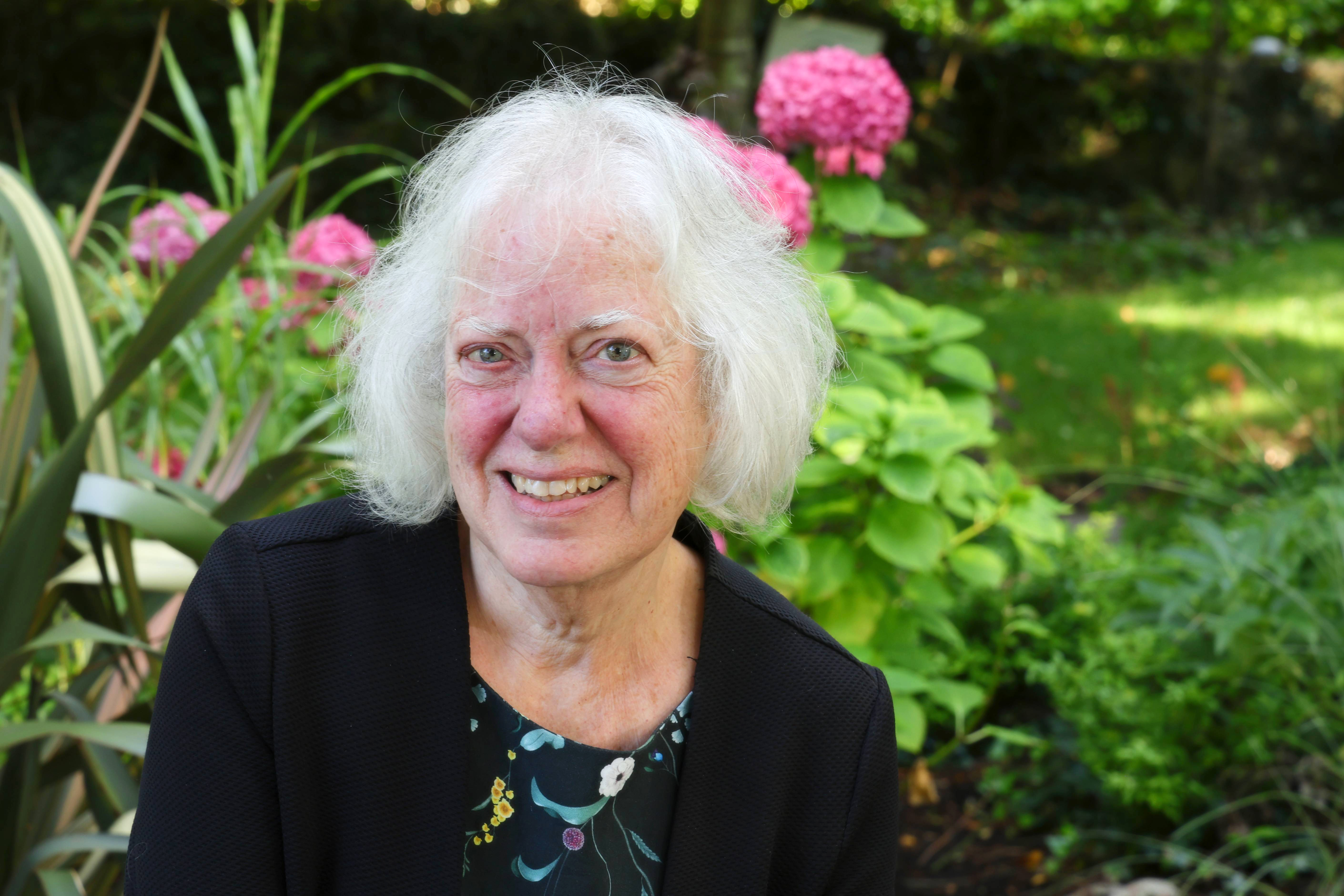 Jane O'Leary, composer, seated in a beautiful garden. Photo Credit: Mike Shaughnessy